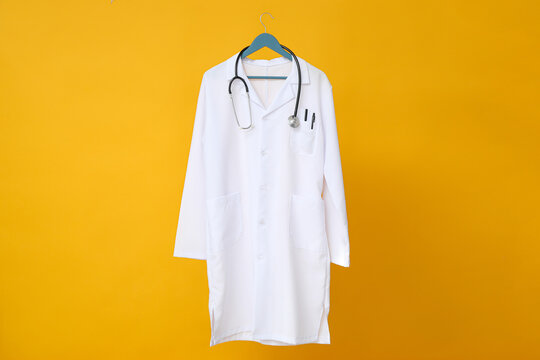 A doctor's white coat with a stethoscope on a yellow background