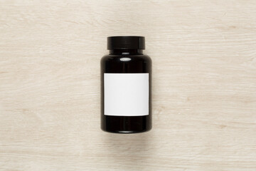 Plastic bottle with vitamins on wooden background, top view