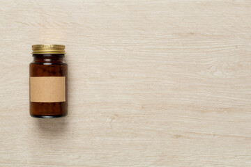 Plastic bottle with vitamins on wooden background, top view