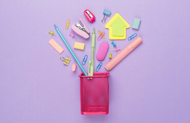 Pink pencil holder with school stationery on color backgroung, top view