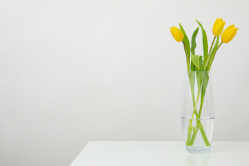 Yellow tulips in a transparent vase on the table