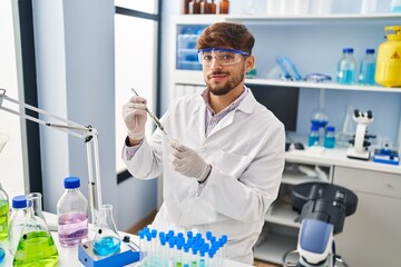 Young arab man scientist analysing plant test tube at laboratory