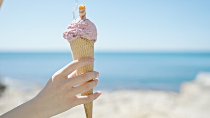 Young chinese woman holding ice cream cone at seaside
