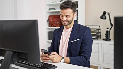 Young hispanic man business worker using computer and smartphone at office