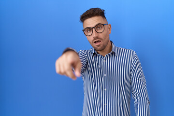 Fototapeta premium Hispanic man with beard wearing glasses pointing displeased and frustrated to the camera, angry and furious with you