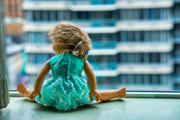 Doll at the window with city skyscrapers view