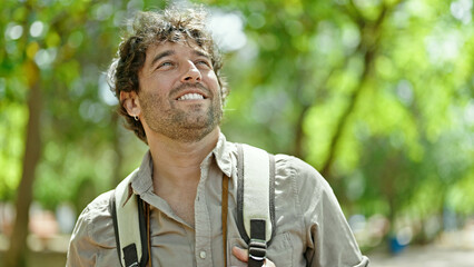 Young hispanic man tourist wearing backpack smiling at park