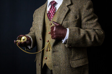 Portrait of Elegant English Gentleman in Tweed Suit and Leather Gloves Holding Pocket Watch. Vintage Style and Retro Fashion.