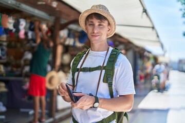 Young caucasian man tourist smiling confident holding wallet with dollars at street market