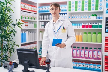 Young caucasian man pharmacist using touchpad and computer at pharmacy