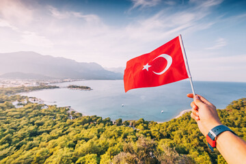 Turkish flag in hand against stunning view of Kemer sea coast and Taurus mountains