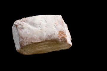 A typical Christmas sweet (Hojaldrina) similar to polvorón and mantecado, made with layers of puff pastry inside, on a black background.