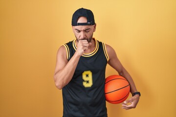 Middle age bald man holding basketball ball over yellow background feeling unwell and coughing as symptom for cold or bronchitis. health care concept.