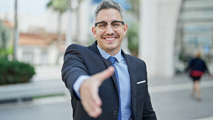 Young hispanic man business worker smiling confident shake hand at street