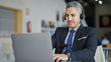 Young hispanic man business worker using laptop and headphones at office
