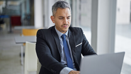 Fototapeta premium Young hispanic man business worker using laptop at office