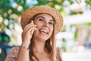 Young woman tourist wearing summer hat talking on smartphone at street
