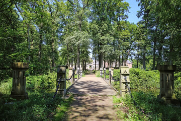 Beautiful hiking and cycle path over bridge through green forest to medieval dutch castle - Kasteel Heeswijk, Noord-Brabant, Netherlands