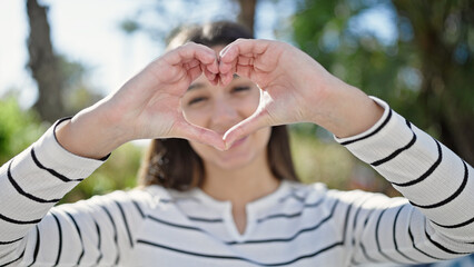 Naklejka premium Young beautiful hispanic woman smiling confident doing heart gesture with hands at park