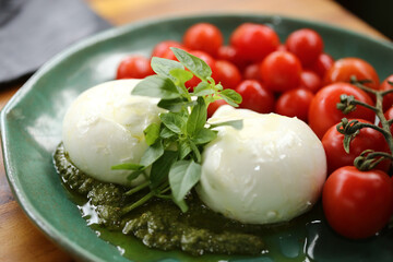 Uma mesa de comidas irresistível em um evento especial. As lindas burratas com tomates em rama e pesto de manjericão são os destaques, trazendo frescor e sabor à celebração.