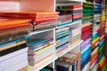 Close-up shelves with assortment of copybooks, sketchbooks, cardboard sheets and color paper in a school stationery shop