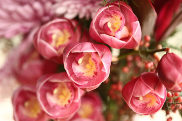 Um encantador arranjo floral com flores em tons de rosa e pequenos abacaxis decorativos, criando uma atmosfera vibrante em uma mesa de evento. © Luciana Serra