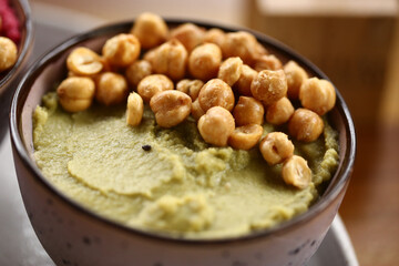 Três deliciosos tipos de homus de grão de bico, servidos com fatias de pão integral. Uma combinação perfeita de sabores e texturas em um evento gastronômico saudável e saboroso.