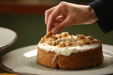 Detalhes que fazem a diferença. Uma delicada mão feminina finaliza a cobertura do bolo com uma noz, trazendo um toque especial e saboroso.