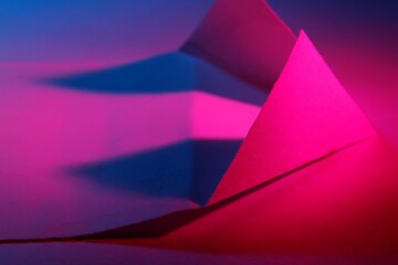Papel de oficina con luz azul-rojo  y magenta forma una figura con triángulos en líneas rectas con sombras geométricas,  formando un bello diseño abstracto con fondo azul en Bokeh - obrazy, fototapety, plakaty