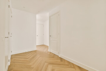 an empty room with white walls and wood flooring on the right, there is a door leading to another room