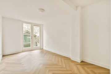 an empty room with white walls and wood flooring, there is a door leading to the left side of the room