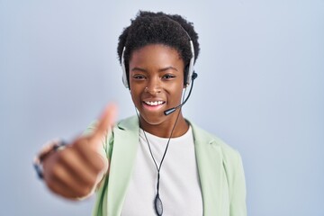 African american woman wearing call center agent headset approving doing positive gesture with hand, thumbs up smiling and happy for success. winner gesture.