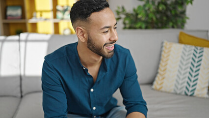 Obraz premium Young hispanic man smiling confident sitting on sofa at home