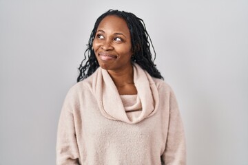 African woman standing over white background smiling looking to the side and staring away thinking.