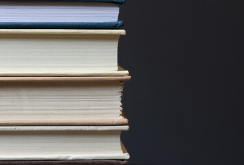 stack of hardcover books in front of dark background with space for copy