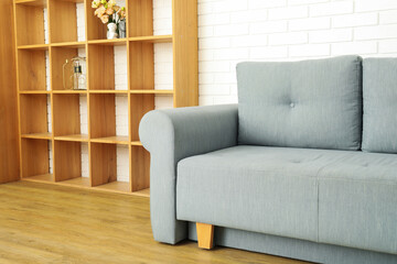 Gray sofa with wooden shelves on the background