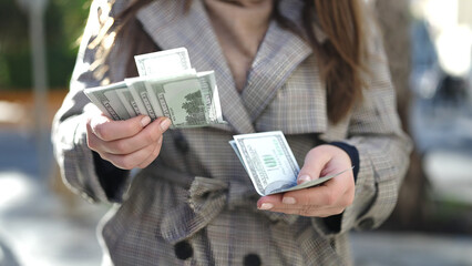 Beautiful hispanic woman counting dollars at street
