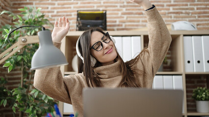 Beautiful hispanic woman business worker dancing using laptop at office