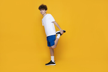 Fototapeta na wymiar A teenager in a sports uniform is doing a warm-up on a yellow background