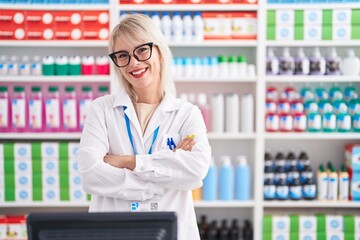 Young caucasian woman working at pharmacy drugstore happy face smiling with crossed arms looking at the camera. positive person.