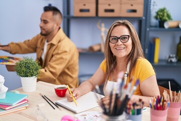 Fototapeta premium Man and woman artists smiling confident drawing at art studio