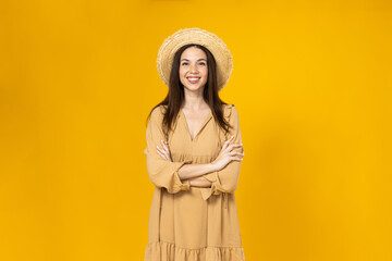 A young woman in a beach hat is smiling on a yellow background