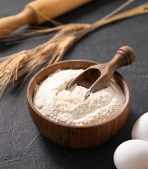 Organic baking ingredients. Wheat flour, eggs and rolling pin on a dark  background close up. Concept of homemade and healthy food