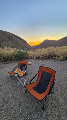 Two camping chair and table with freshly made American burgers during sunset at Wildrose camping ground in Death Valley National Park, California, USA, United States of America. Camp in the mountains