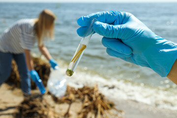 A test tube with river water in hands in blue gloves