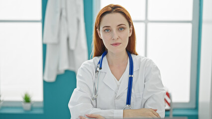 Young redhead woman doctor wearing stethoscope with serious expression at clinic