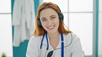 Young redhead woman doctor doing video call with headset at clinic
