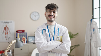 Young hispanic man doctor smiling confident standing with crossed arms at clinic