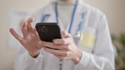 Young hispanic man doctor using smartphone at clinic