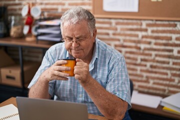 Middle age grey-haired man business worker using laptop drinking coffee at office
